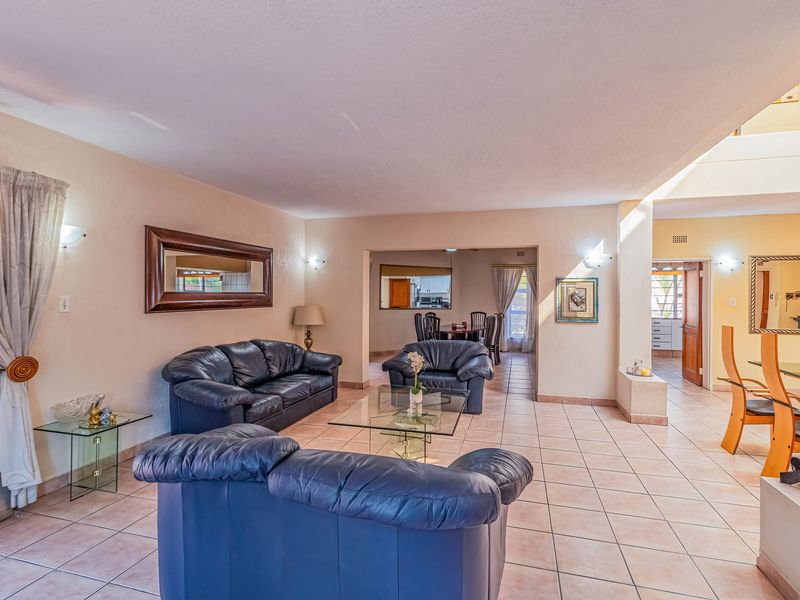 Spacious open-plan living and dining area featuring neutral tiled flooring and a functional layout connecting to the kitchen and adjacent spaces.