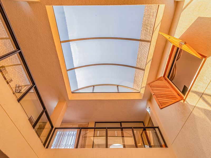 An internal atrium or light well featuring a curved polycarbonate skylight, glass balustrades, and timber shutters, providing natural light to the interior space.