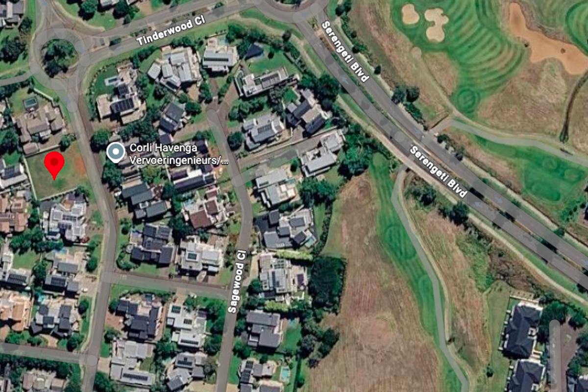 Aerial view of a vacant residential plot situated within a developed estate, adjacent to established homes and golf course surroundings.
