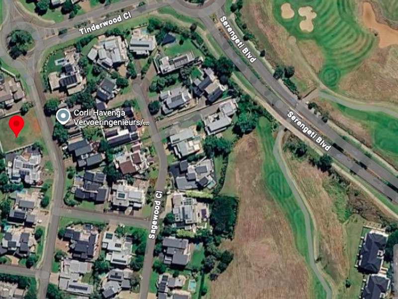 Aerial view of a vacant residential plot situated within a developed estate, adjacent to established homes and golf course surroundings.