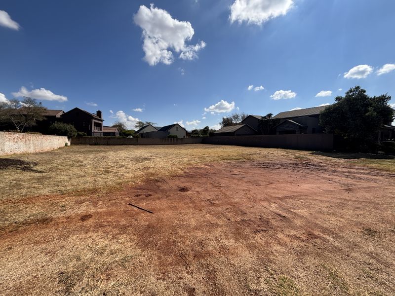A vacant residential plot featuring level ground and established boundary walls, situated within a developed neighborhood.
