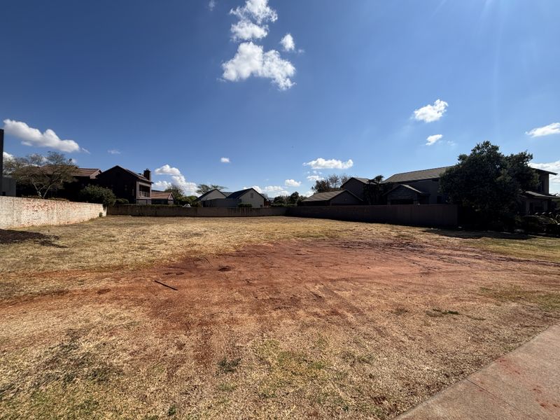 A vacant residential plot featuring cleared land and perimeter boundary walls, offering a blank canvas for new construction in a developed neighborhood.