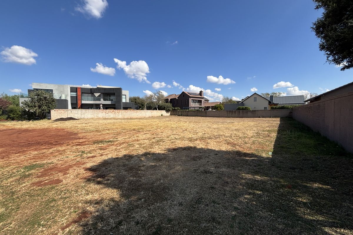 A vacant residential plot featuring a level surface enclosed by perimeter boundary walls, situated in an established neighborhood.