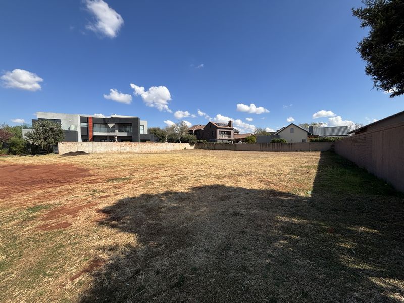 A vacant residential plot featuring a level surface enclosed by perimeter boundary walls, situated in an established neighborhood.