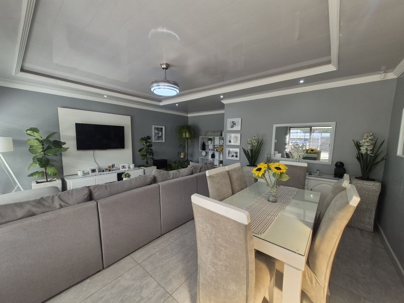 Spacious open-plan living and dining area featuring modern tiled flooring, a recessed ceiling with integrated lighting, and a ceiling fan.