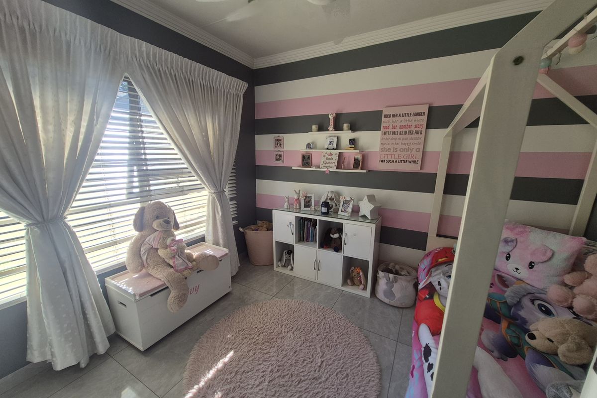 A well-maintained bedroom featuring tiled flooring, a ceiling fan, and decorative striped wall finishes with ample natural light from the window.