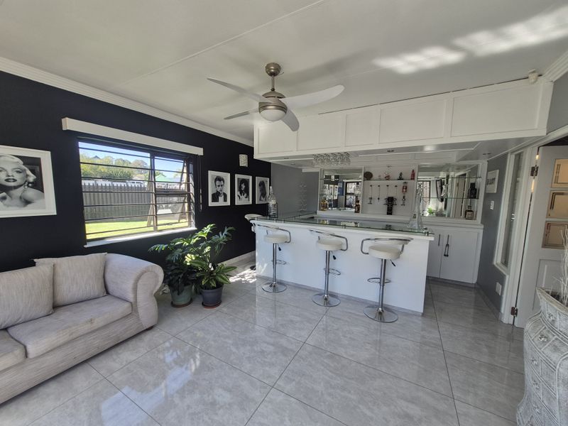 A well-appointed home bar area featuring a built-in counter, mirrored back bar, overhead storage cabinetry, and modern tiled flooring.