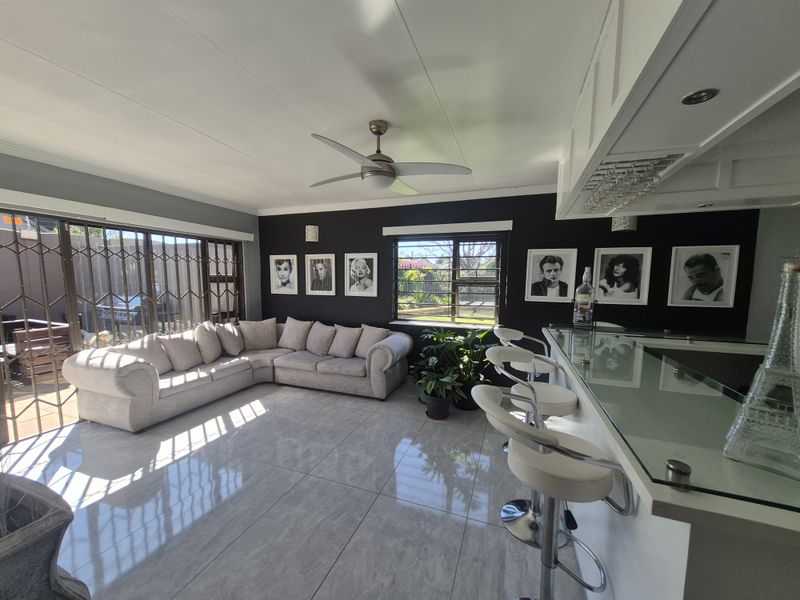 Spacious open-plan living area featuring a built-in bar, modern tiled flooring, ceiling fan, and large sliding doors providing access to the outdoor space.