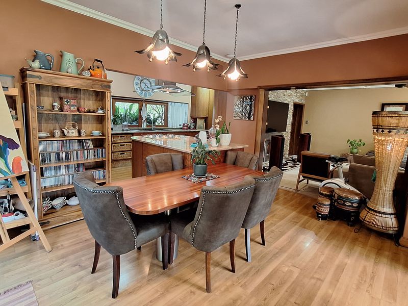 Open-plan living and dining area featuring laminate flooring, pendant lighting, and a kitchen island with stone countertops.