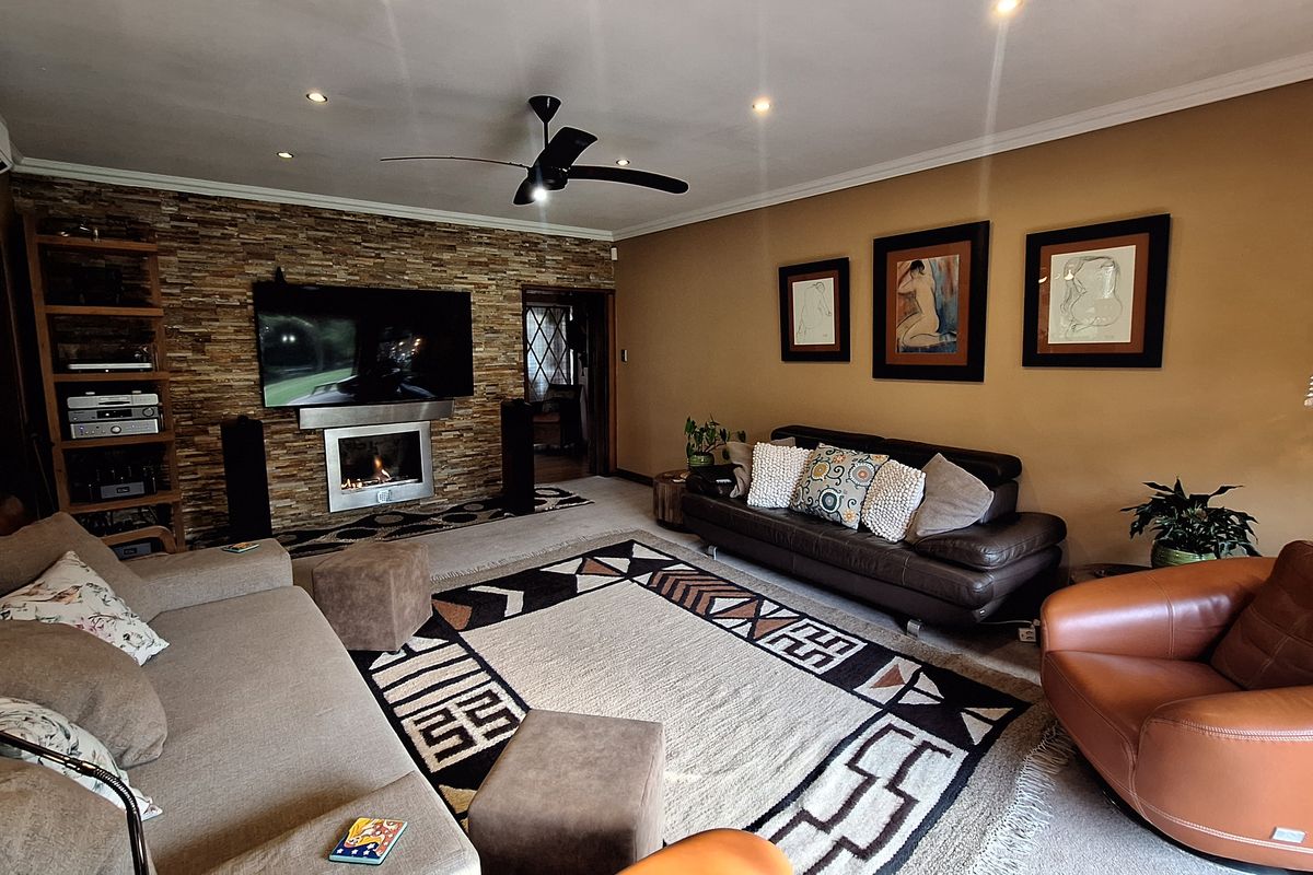 Spacious living room featuring a stone accent wall with a built-in fireplace, recessed lighting, and a ceiling fan.