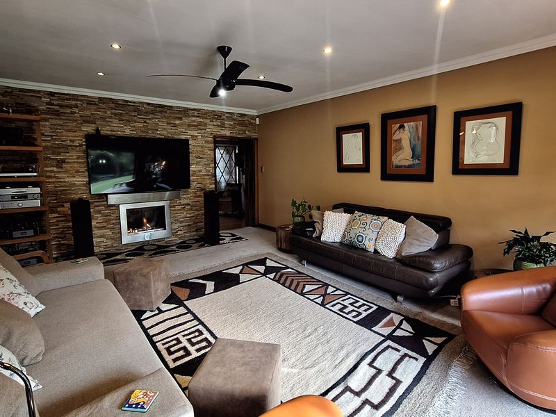 Spacious living room featuring a stone accent wall with a built-in fireplace, recessed lighting, and a ceiling fan.