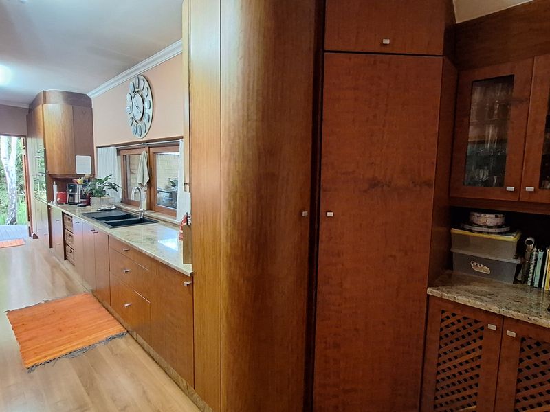 A functional kitchen featuring extensive wood cabinetry, stone countertops, and direct access to an outdoor deck area.