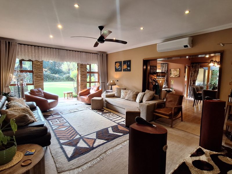 Spacious living room featuring recessed lighting, a ceiling fan, split-system air conditioning, and large sliding glass doors opening to the garden.