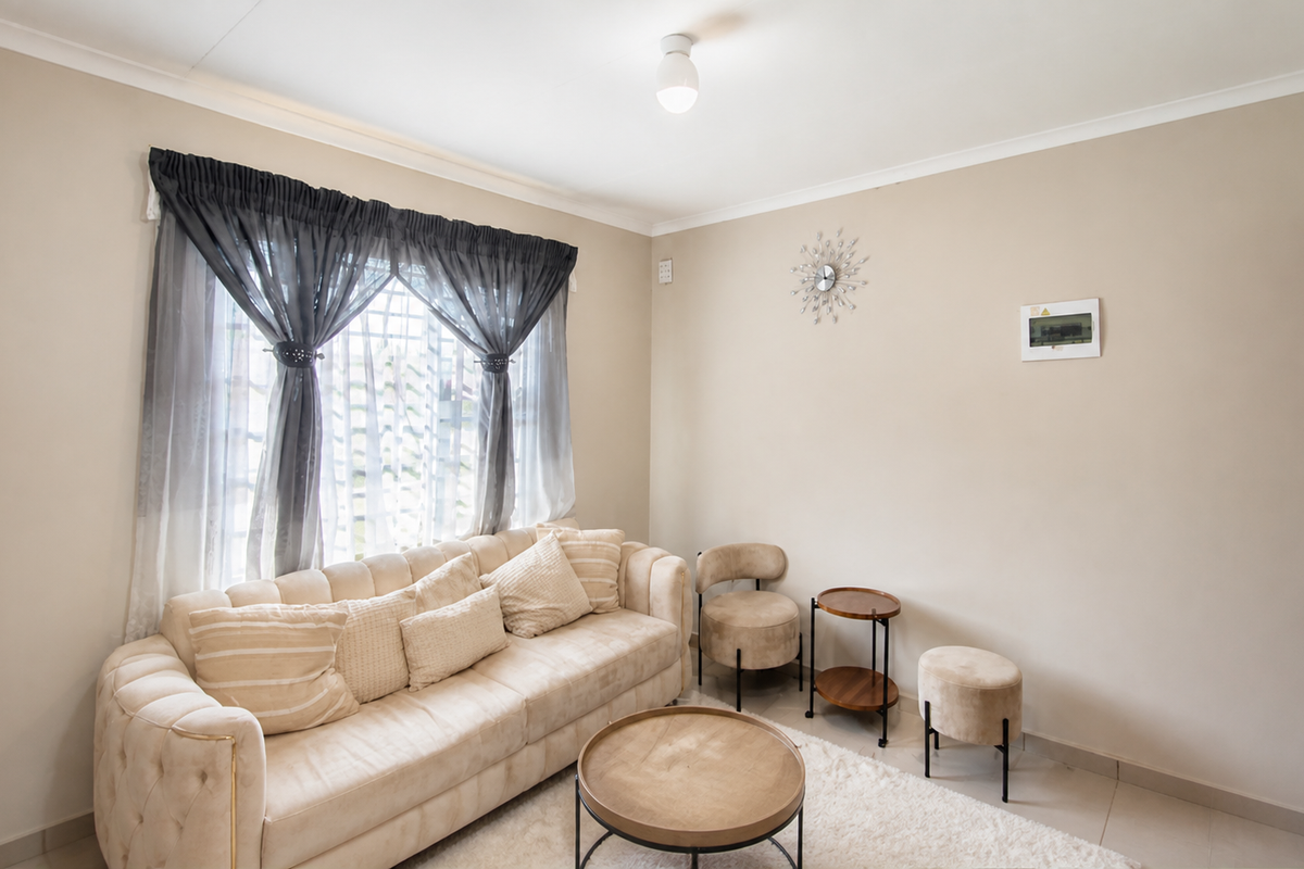 A well-maintained living room featuring neutral wall tones, tiled flooring, and decorative cove cornicing, providing a bright and comfortable living space.