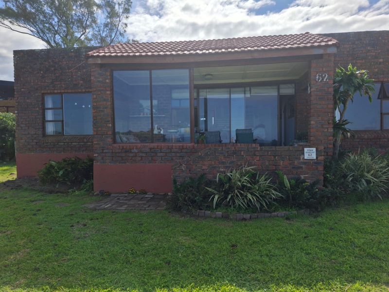 Front elevation of a face brick house featuring a covered patio area with large sliding glass doors and a tiled roof.