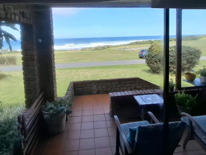 A covered patio featuring brick pillars and tiled flooring, offering an open view of the surrounding landscape and ocean.