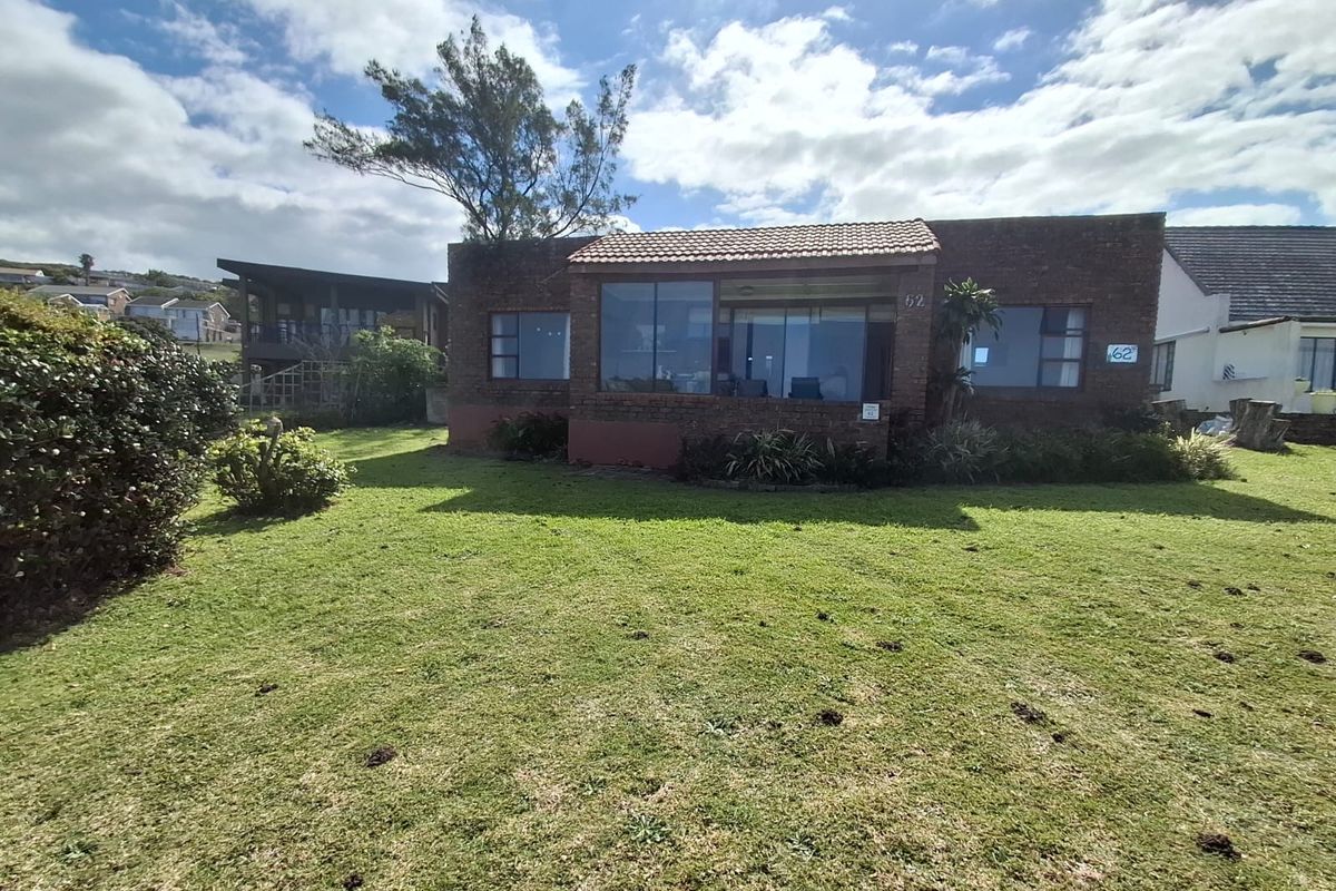 Rear view of a face brick house featuring a tiled roof, large windows, and a spacious surrounding lawn area.