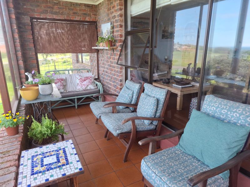 A covered patio area featuring exposed brick walls, tiled flooring, and large sliding glass doors providing access to the interior living space.