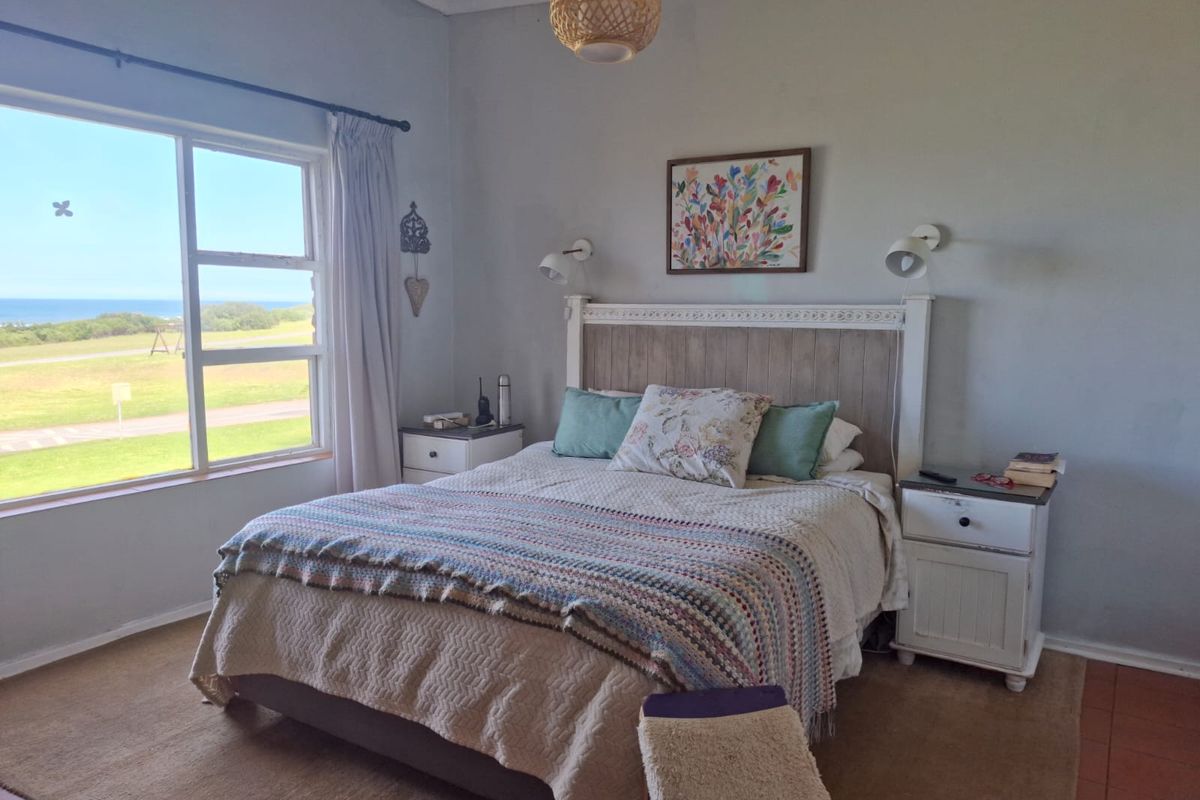 A bedroom featuring a large window with coastal views, wall-mounted lighting, and tiled flooring.