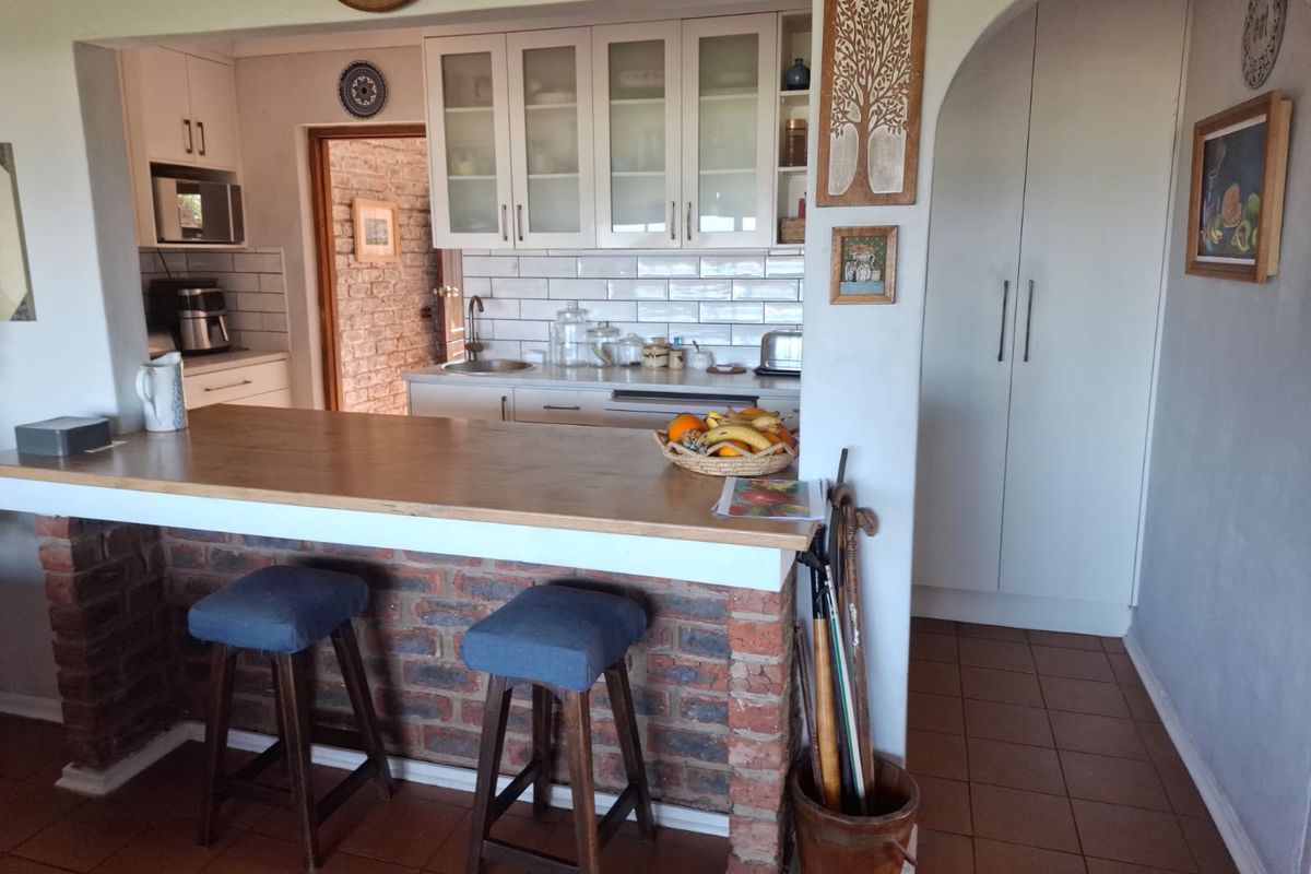 A functional kitchen featuring a brick-based breakfast bar with a wooden countertop, subway tile backsplash, and ample built-in cabinetry.