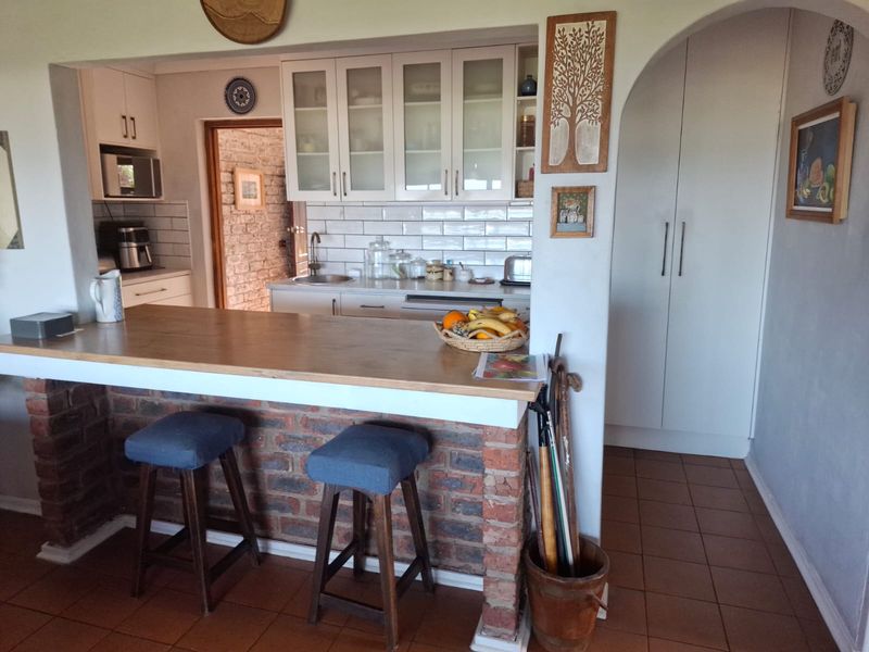 A functional kitchen featuring a brick-based breakfast bar with a wooden countertop, subway tile backsplash, and ample built-in cabinetry.