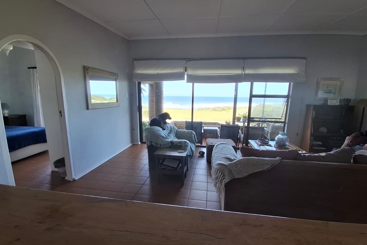 Spacious living room featuring tiled flooring, an arched entryway, and large sliding glass doors that provide natural light and scenic ocean views.