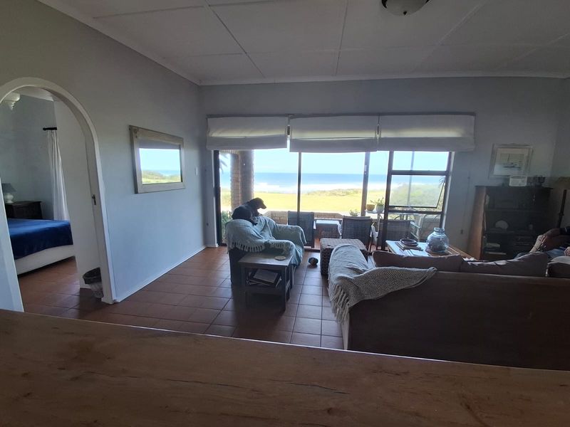 Spacious living room featuring tiled flooring, an arched entryway, and large sliding glass doors that provide natural light and scenic ocean views.