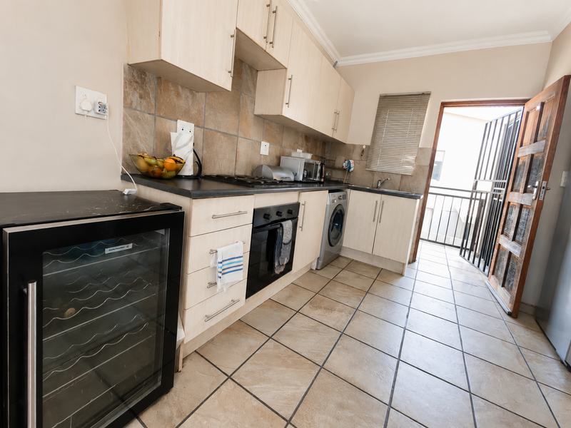 Functional kitchen featuring light wood cabinetry, tiled backsplash, built-in oven with gas hob, and direct access to an outdoor balcony area.