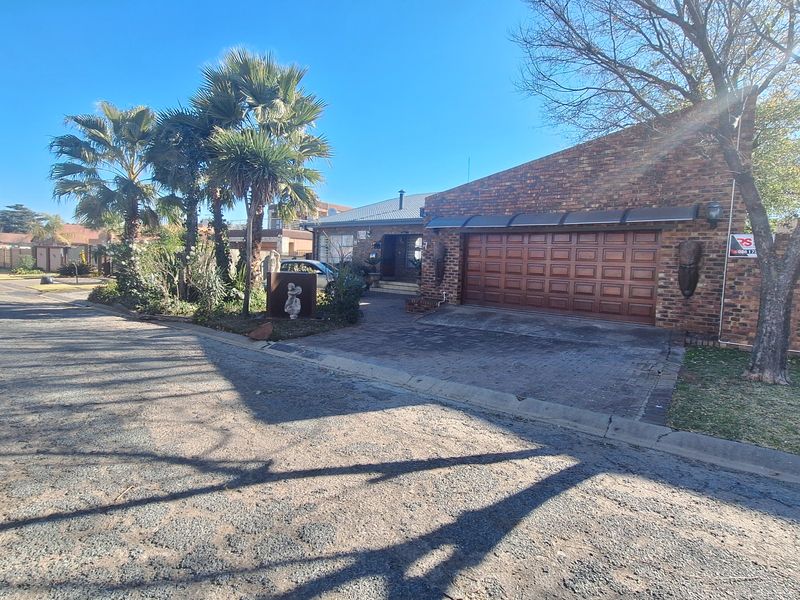 Front view of a brick-faced house featuring a double garage, paved driveway, and established garden area.