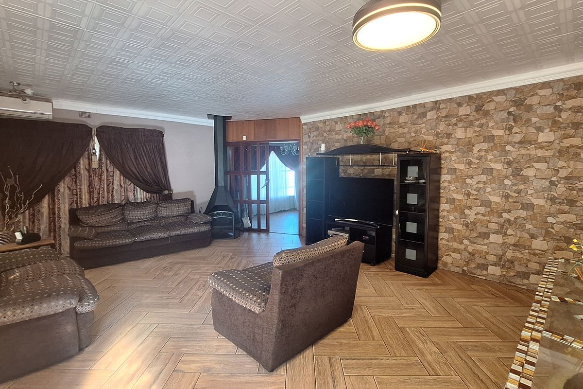 Spacious living room featuring herringbone tile flooring, a stone veneer feature wall, and a freestanding fireplace, offering a comfortable and functional living space.