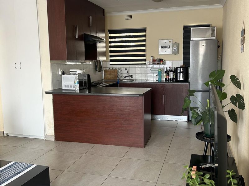 Open plan kitchen featuring dark wood cabinetry, laminate countertops, and tiled flooring, seamlessly integrated with the living area.
