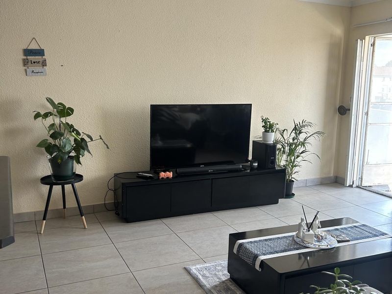 A living room featuring neutral tiled flooring and a sliding glass door providing access to the exterior.