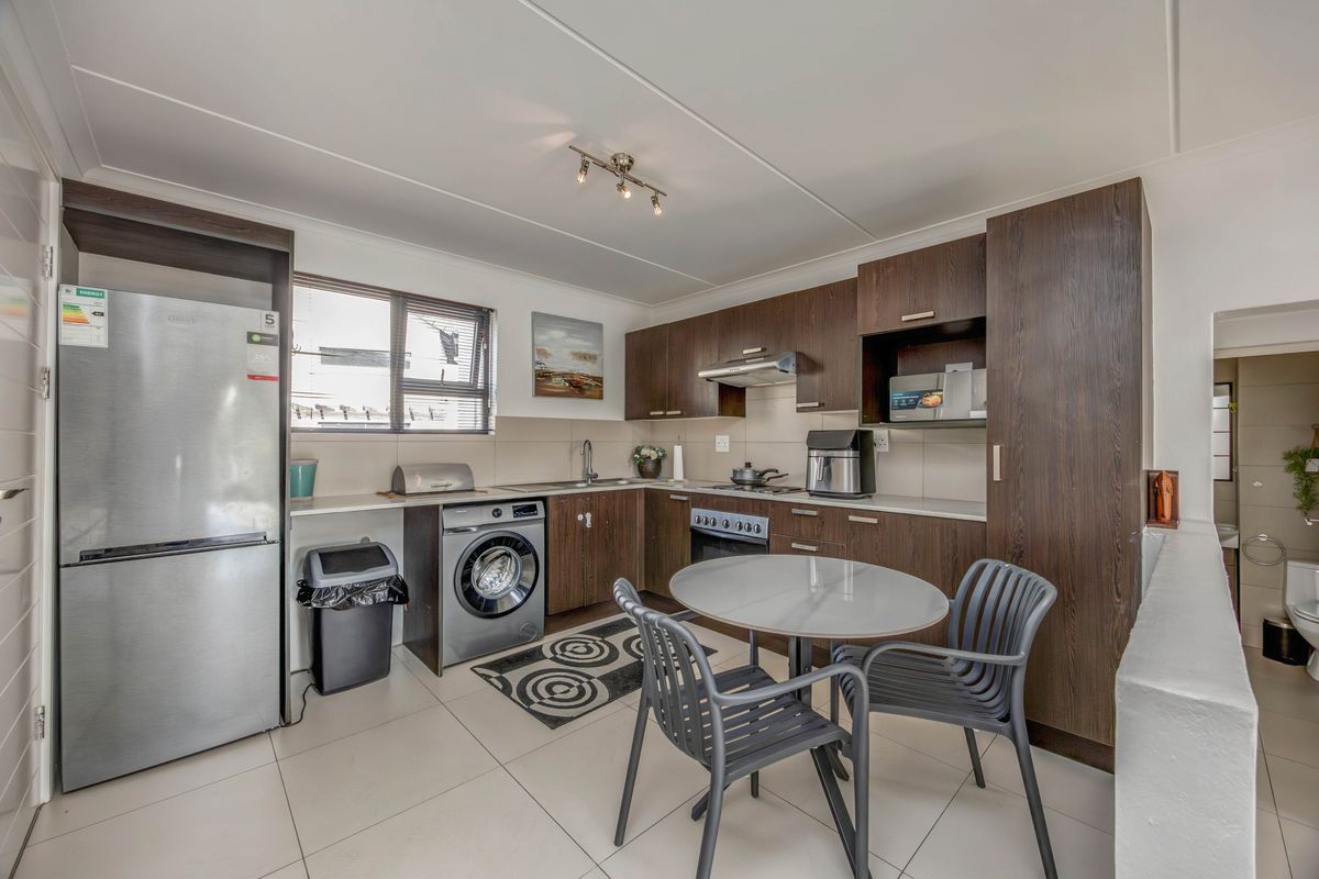A functional kitchen featuring dark wood cabinetry, tiled flooring, a built-in oven with hob, and an integrated extractor fan.