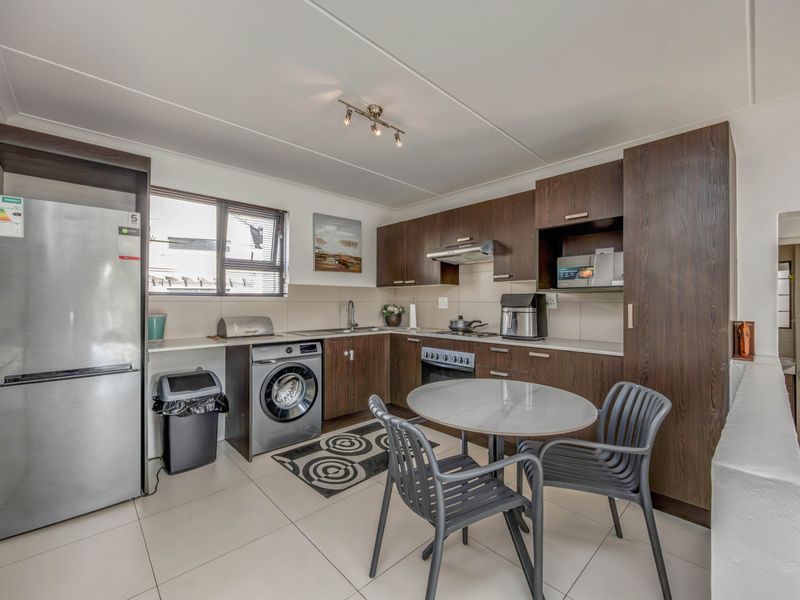 A functional kitchen featuring dark wood cabinetry, tiled flooring, a built-in oven with hob, and an integrated extractor fan.