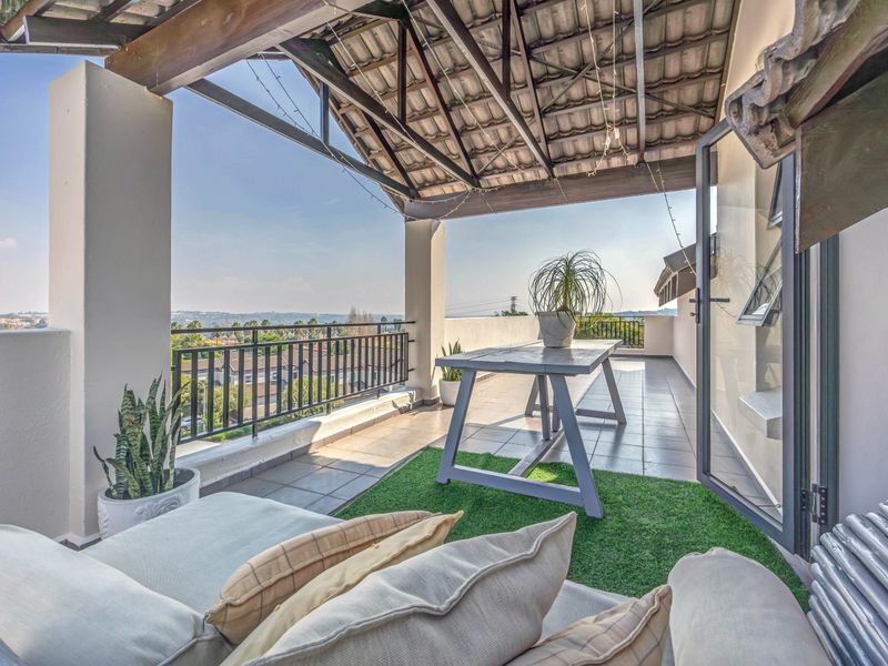 A covered balcony featuring tiled flooring, a timber roof structure, and a metal balustrade, offering elevated views of the surrounding area.