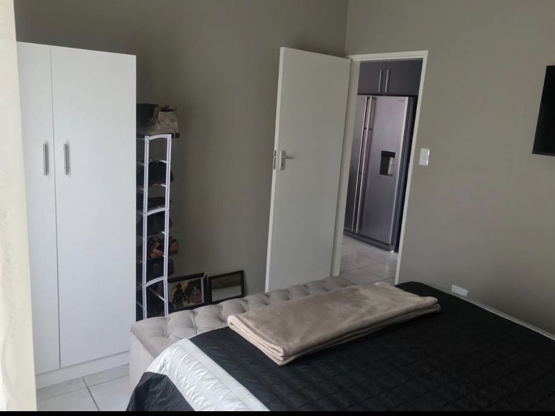 A bedroom featuring a built-in wardrobe with a view into an adjacent kitchen area.