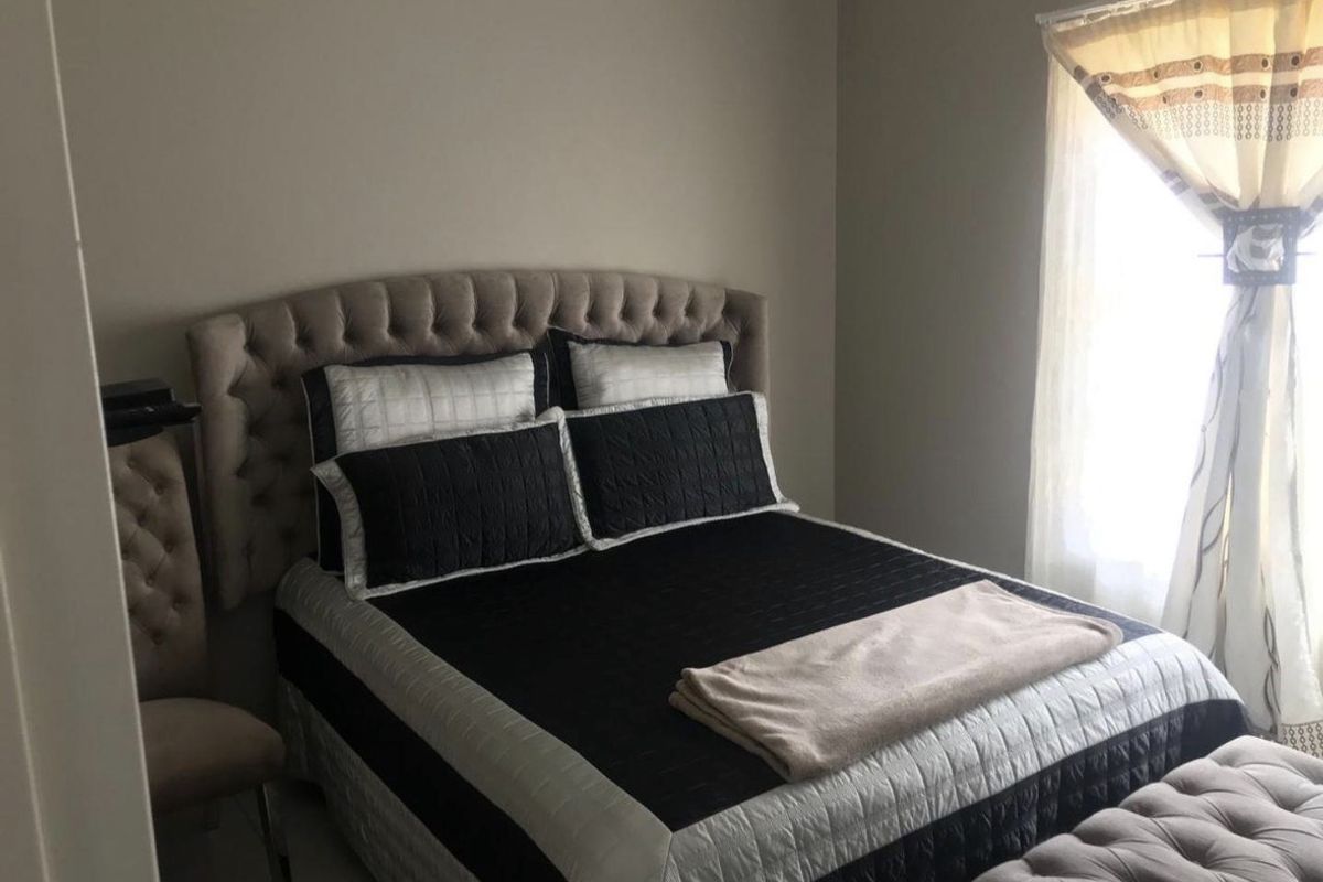 A standard bedroom featuring neutral wall tones and natural light from a side window.