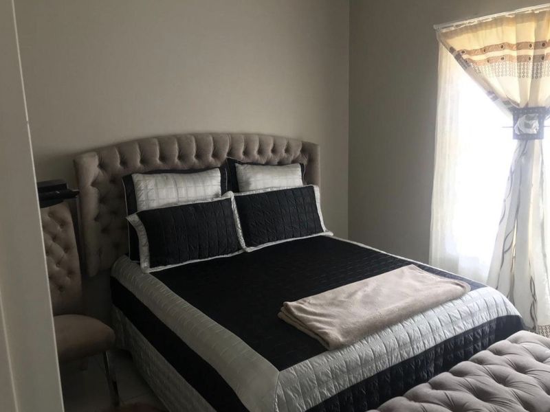 A standard bedroom featuring neutral wall tones and natural light from a side window.