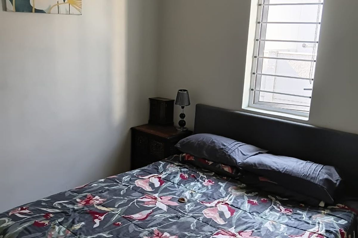 A functional bedroom featuring tiled flooring, a window with security bars, and a roller blind.