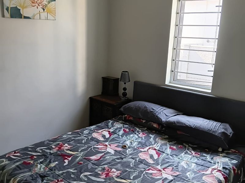 A functional bedroom featuring tiled flooring, a window with security bars, and a roller blind.