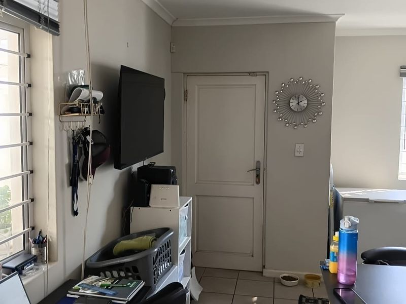 A functional kitchen area featuring tiled flooring, coving, and a secure internal door, currently utilized as a multi-purpose workspace.