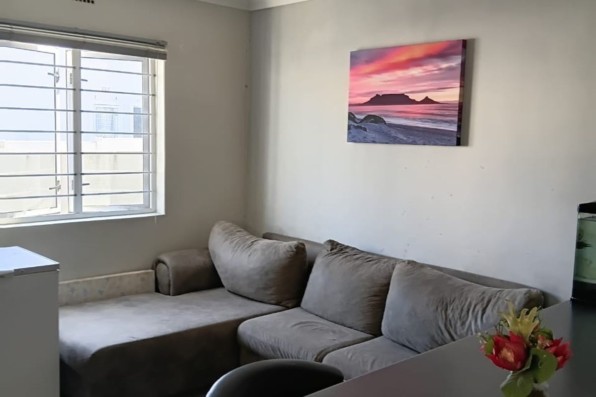 A living room area featuring a window with security burglar bars and neutral wall finishes.