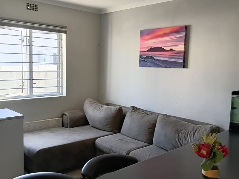 A living room area featuring a window with security burglar bars and neutral wall finishes.