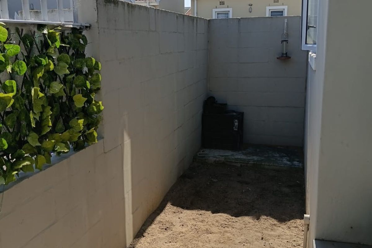A small, enclosed rear courtyard area featuring concrete block boundary walls and a paved section, currently awaiting landscaping or further development.