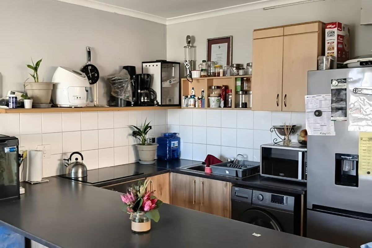 A functional kitchen featuring laminate countertops, built-in cabinetry, and a tiled splashback, providing a practical workspace with integrated sink and storage solutions.