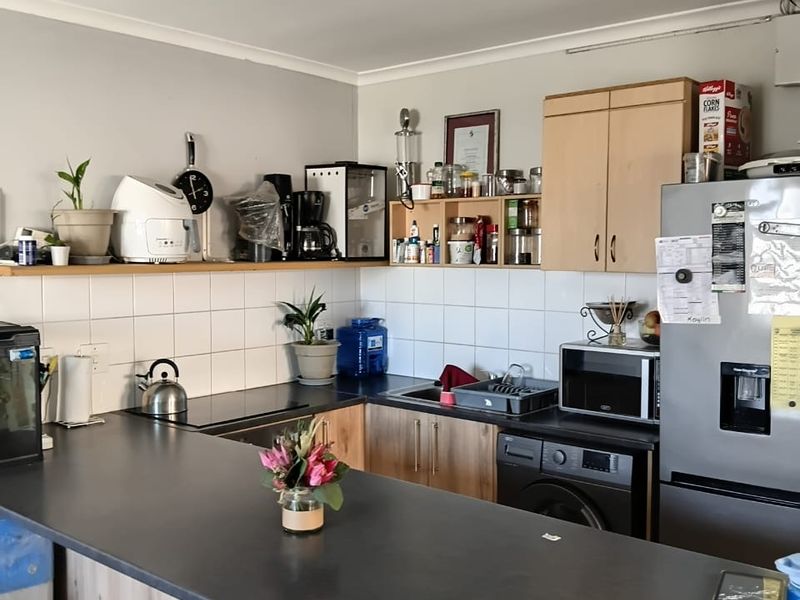 A functional kitchen featuring laminate countertops, built-in cabinetry, and a tiled splashback, providing a practical workspace with integrated sink and storage solutions.