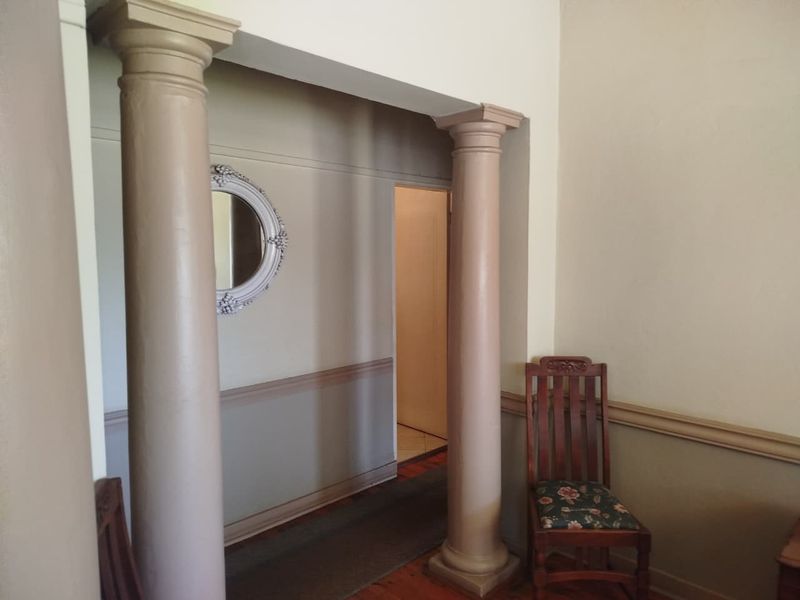 A hallway featuring decorative columns and wainscoting, providing a classic architectural transition between living spaces.