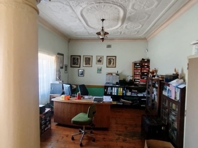 A home office featuring original hardwood flooring and an ornate period plaster ceiling, providing a character-filled workspace.