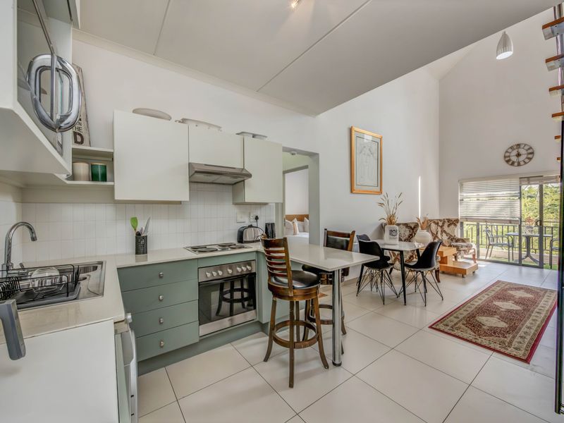 Open-plan kitchen and living area featuring modern cabinetry, built-in appliances, tiled flooring, and access to a balcony through sliding glass doors.