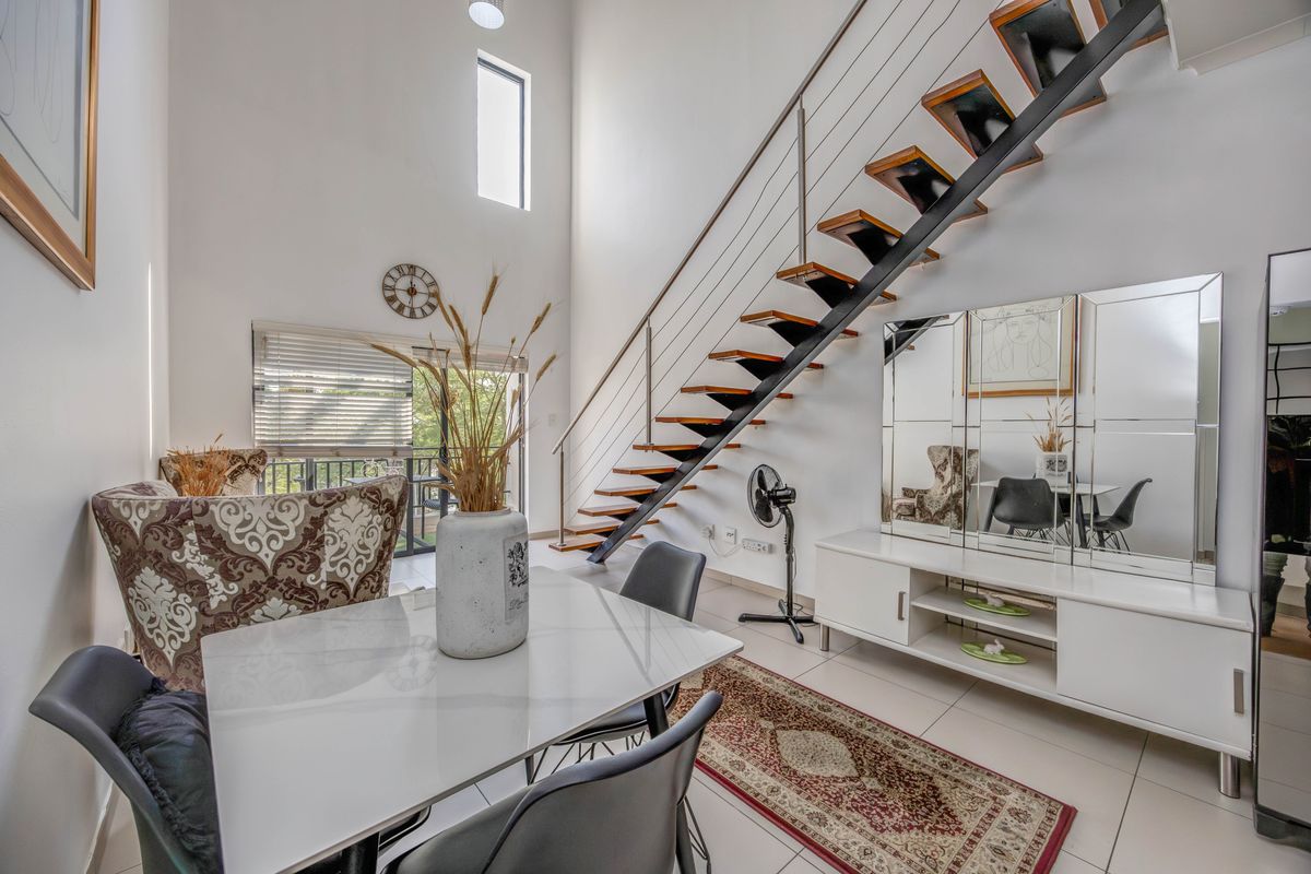 Spacious living area featuring high ceilings, tiled flooring, and a modern open-tread staircase with a stainless steel balustrade leading to the upper level.